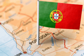 Pequeno alfinete com a bandeira de Portugal fincado em um mapa que destaca o território português, com a cidade de Lisboa visível em destaque.